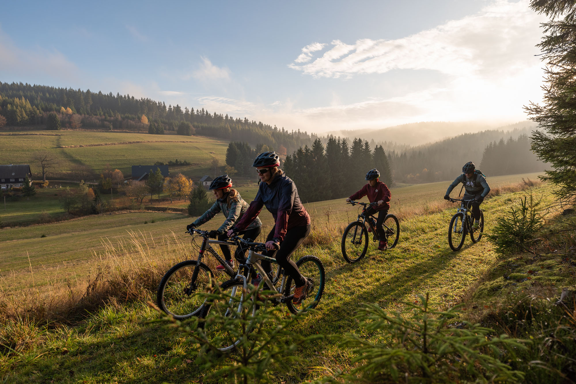 Vier Fahrradfahrer, die gemeinsam auf einer Wiese Fahrrad fahren.