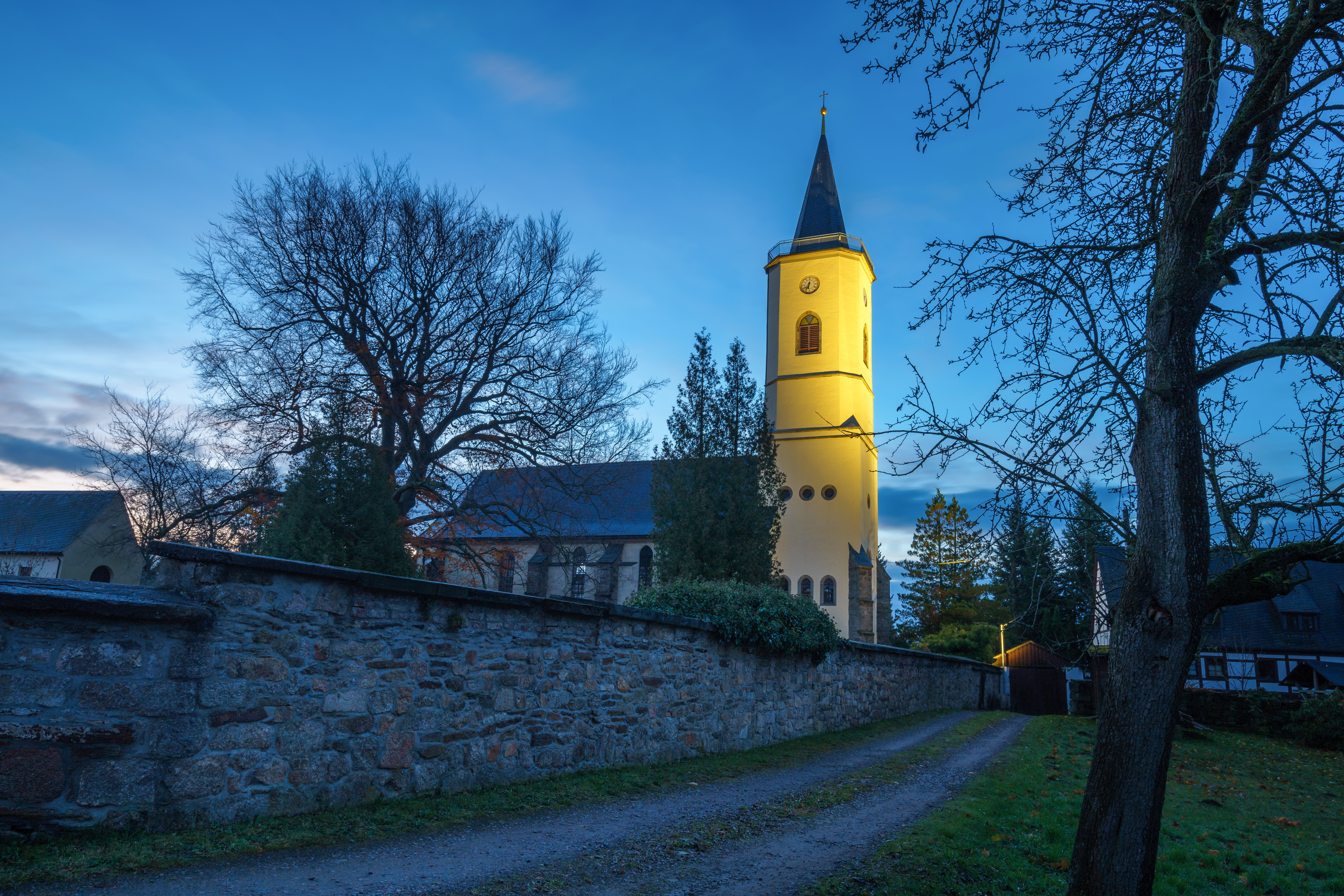 Eine Kirche mit angestrahltem Kirchturm. 