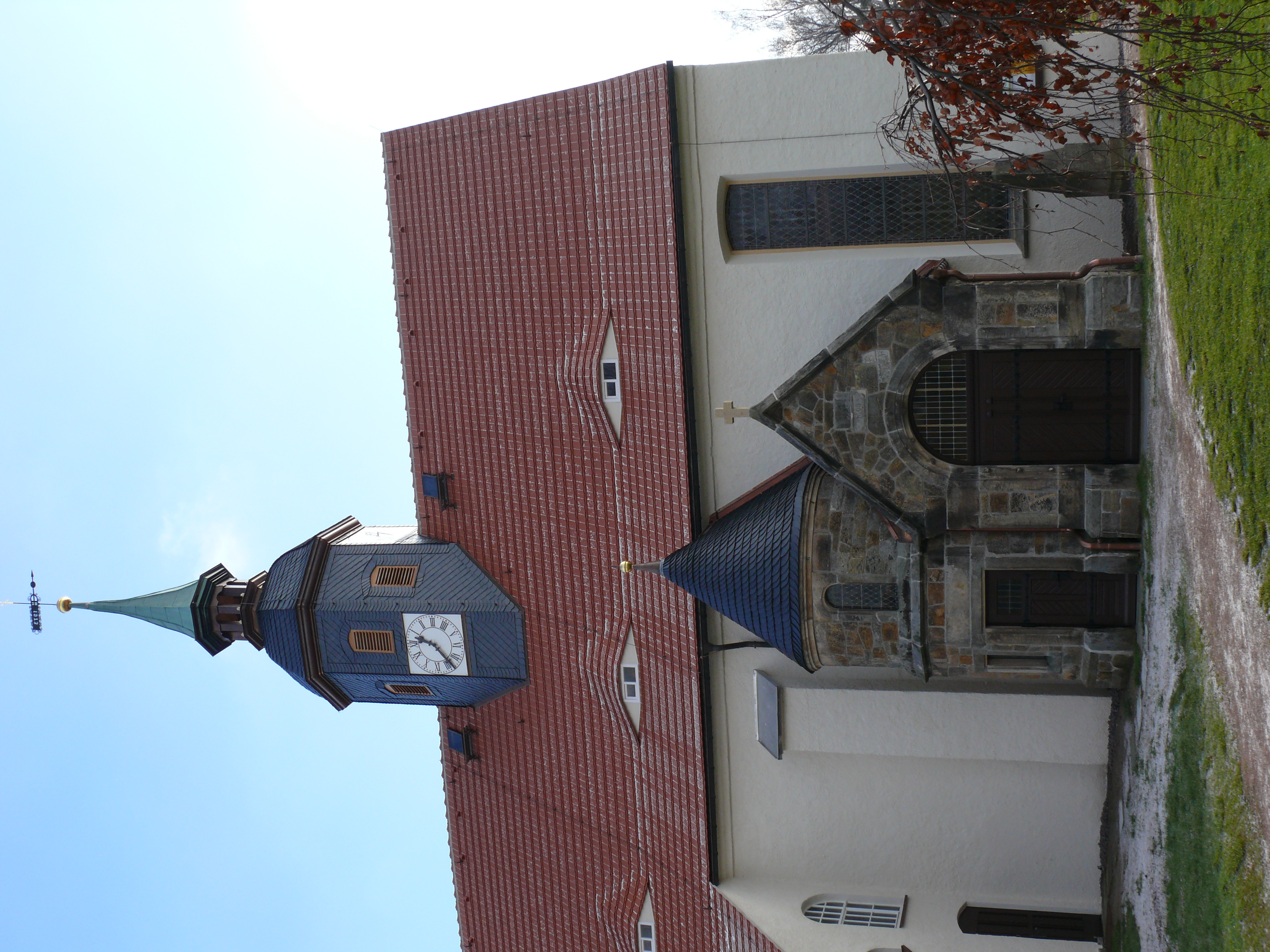 Frontalansicht einer Kirche mit Kirchturm und steinernem Eingang.