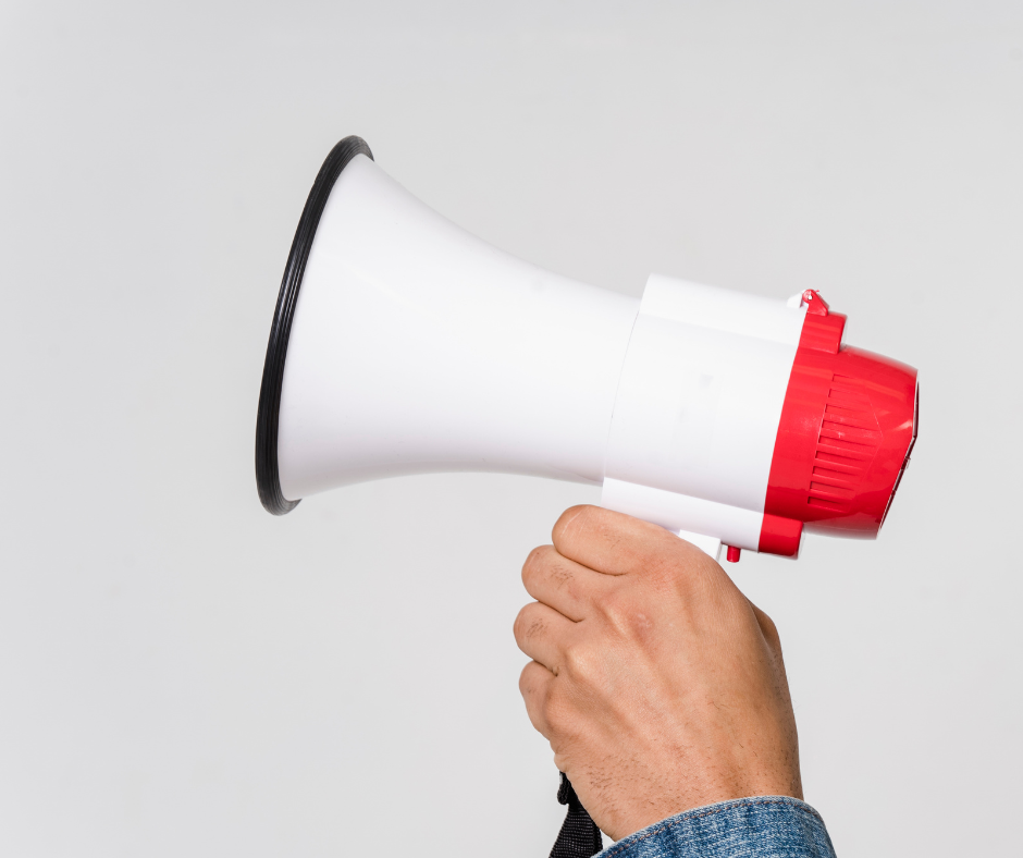 Ein in einer Hand gehaltenes rot weißes Megaphone. 