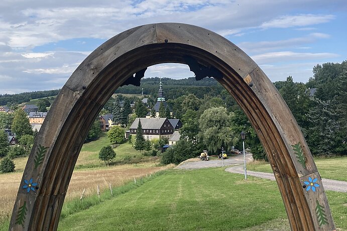 Holzbogen als Durchgang mit Blick auf Seiffen im Hintergrund.