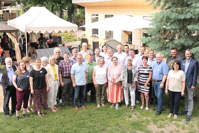 ca. 30 Personen im Halbkreis stehend und in die Kamera lächelnd