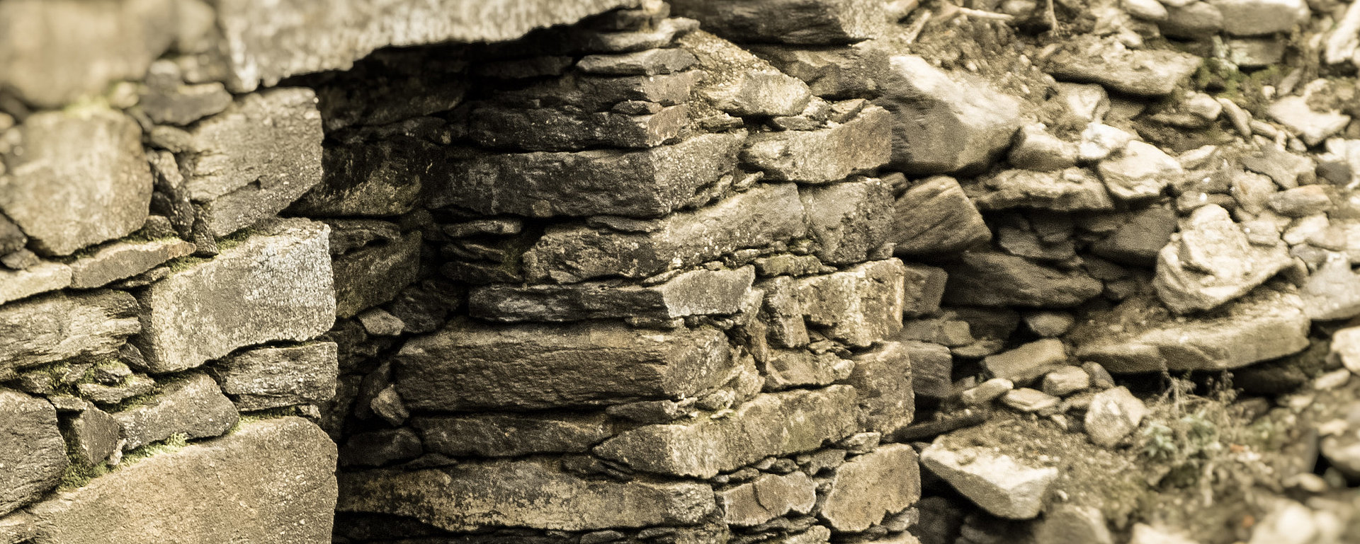 Graue Natursteinmauer mit Eingang